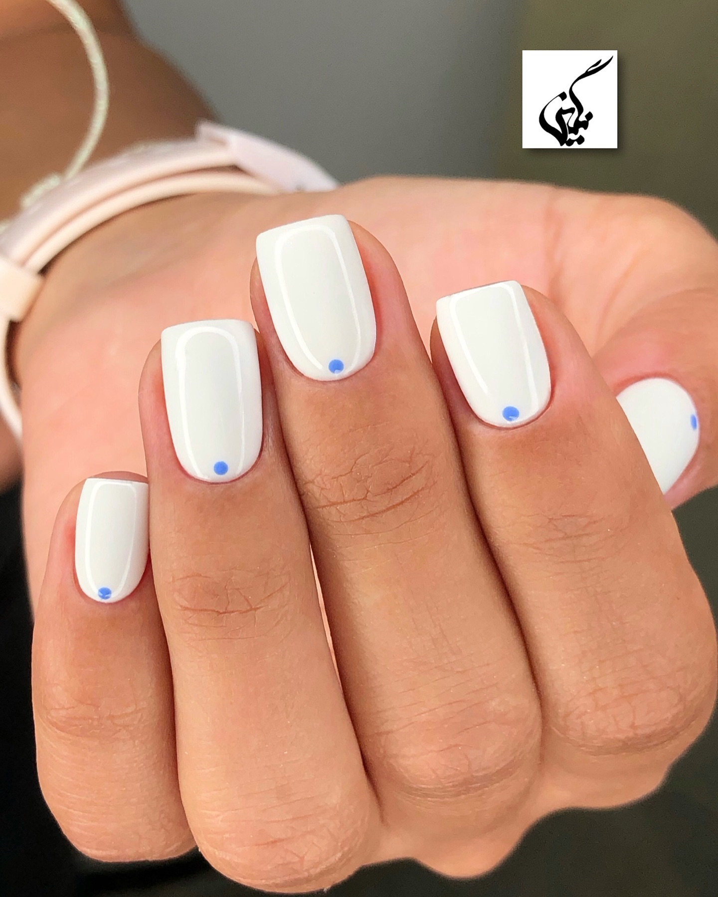 Short square nails with white polish and blue dot accent