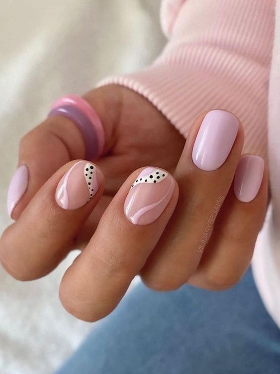 Pastel pink nails with dot accents, artistic and stylish design.