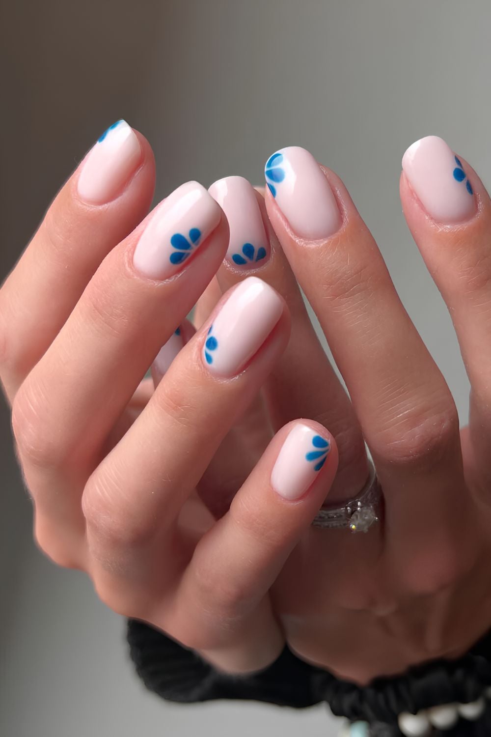 White nails with blue petal accents, minimalist design.