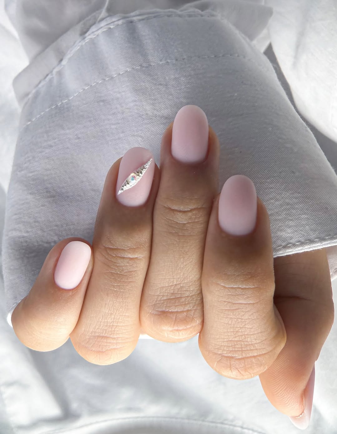Soft pink matte nails with gem accent, elegant and subtle