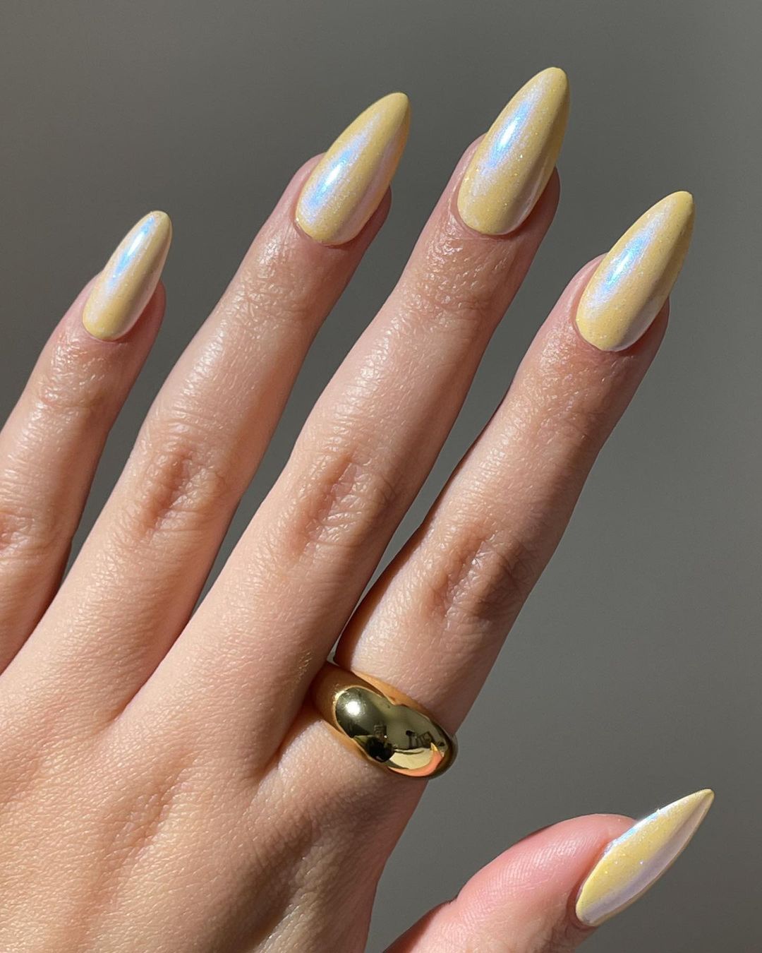 Pearlescent yellow nails with almond shape and shimmer finish
