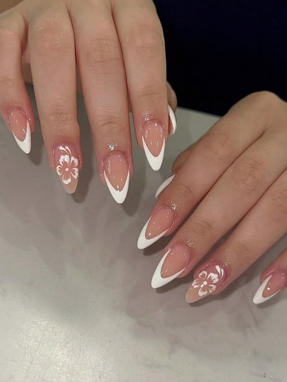 White French tips with floral accents on almond nails.
