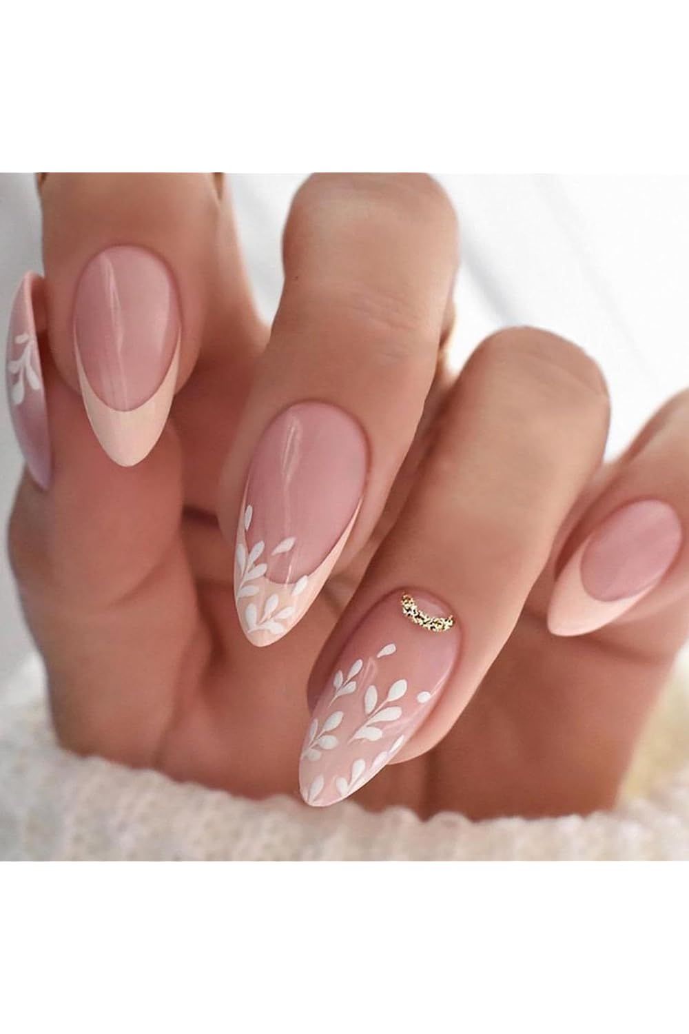 Nude and white French tips with leafy details on oval nails.