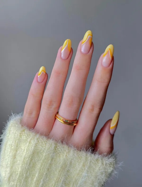 Yellow swirl nail art on long almond nails.