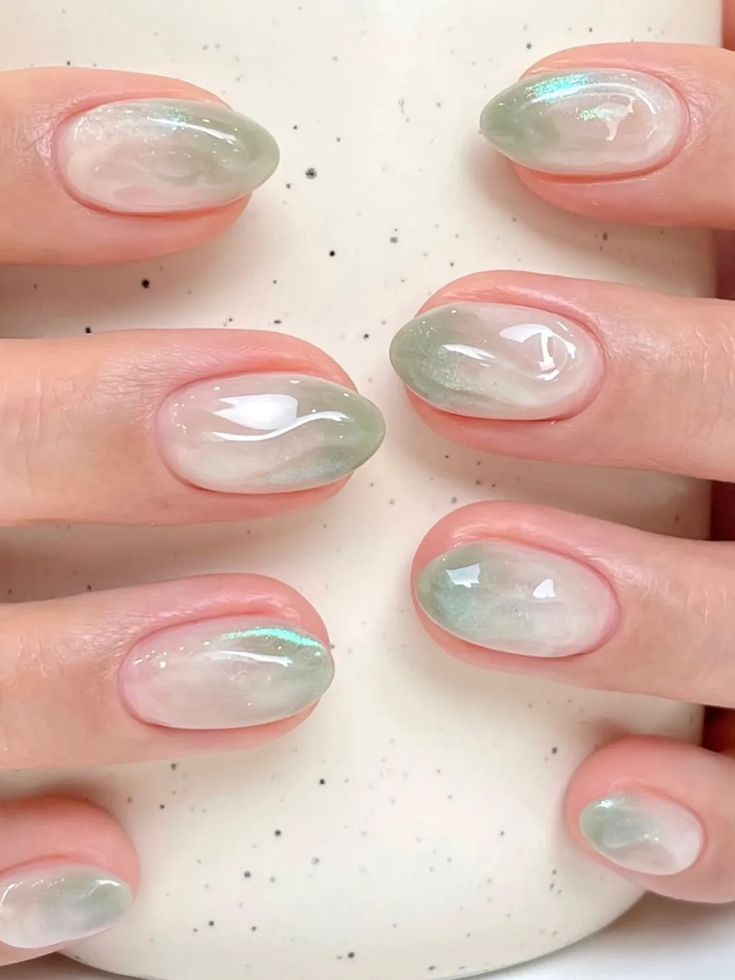 Green aura nails with glossy finish on almond nails.