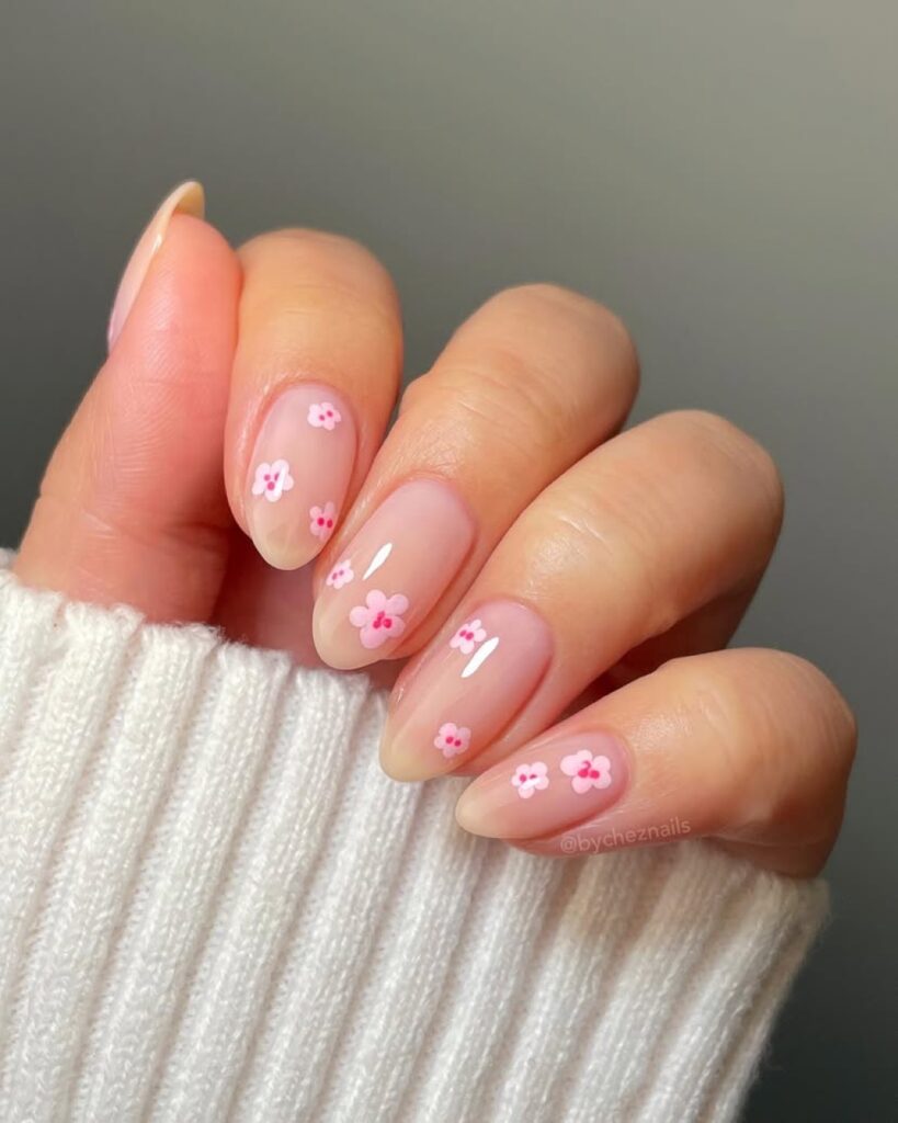 Sheer nails with pink floral accents on almond shape.