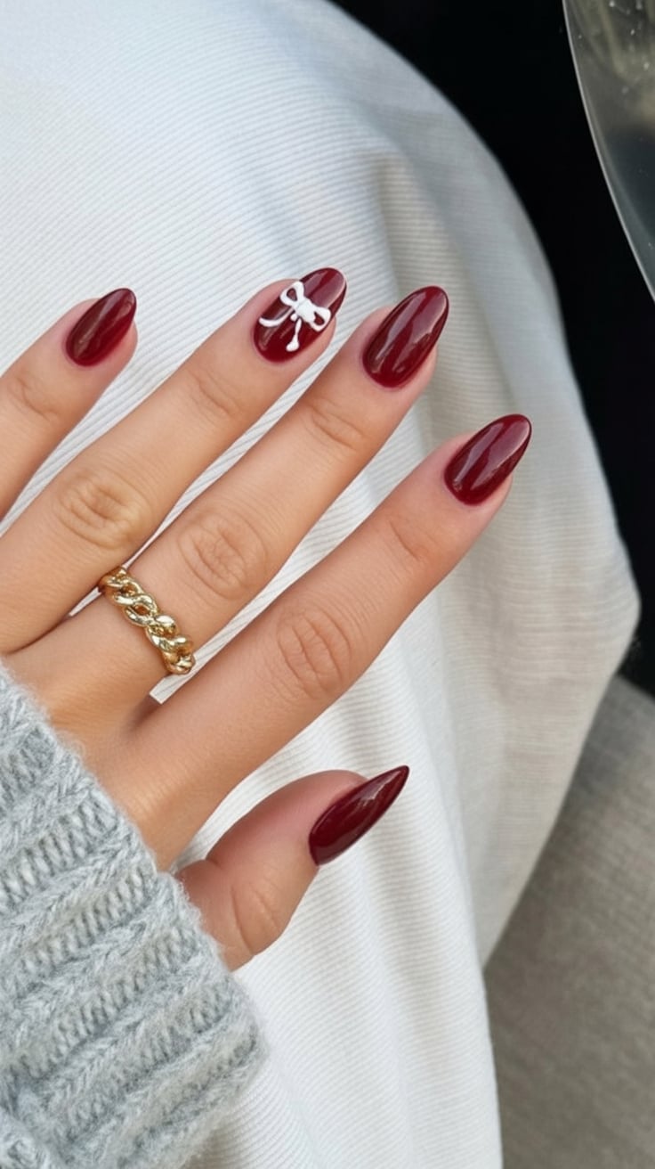 Almond nails with berry polish and bow design.
