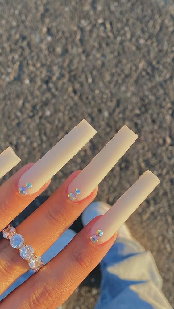 Long coffin nails with matte nude polish and crystal accents.