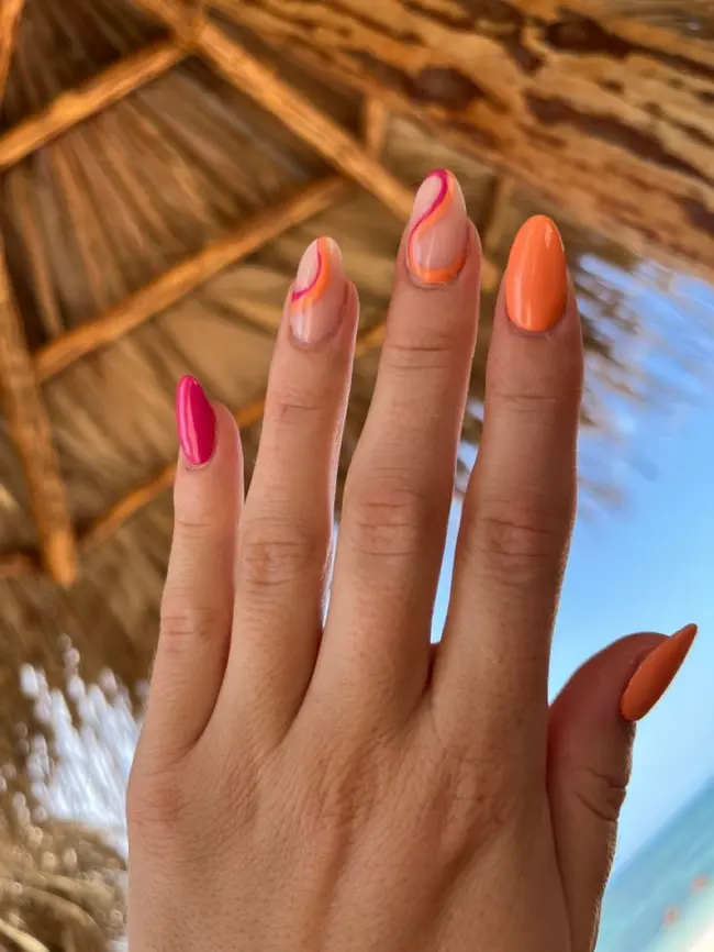 Vibrant orange and pink swirl nails, ideal for tropical vacations and sunset inspirations