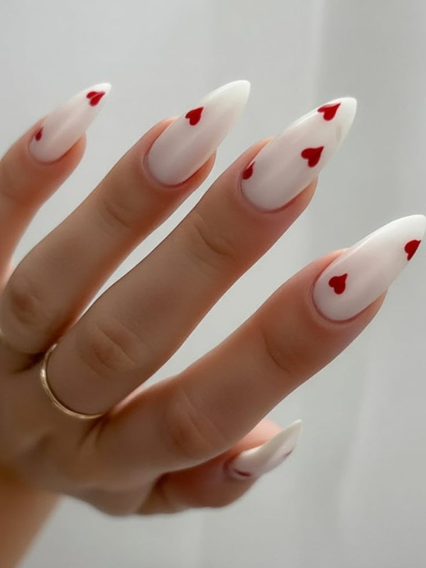 White nails with red heart accents, ideal for romantic vacations and playful designs