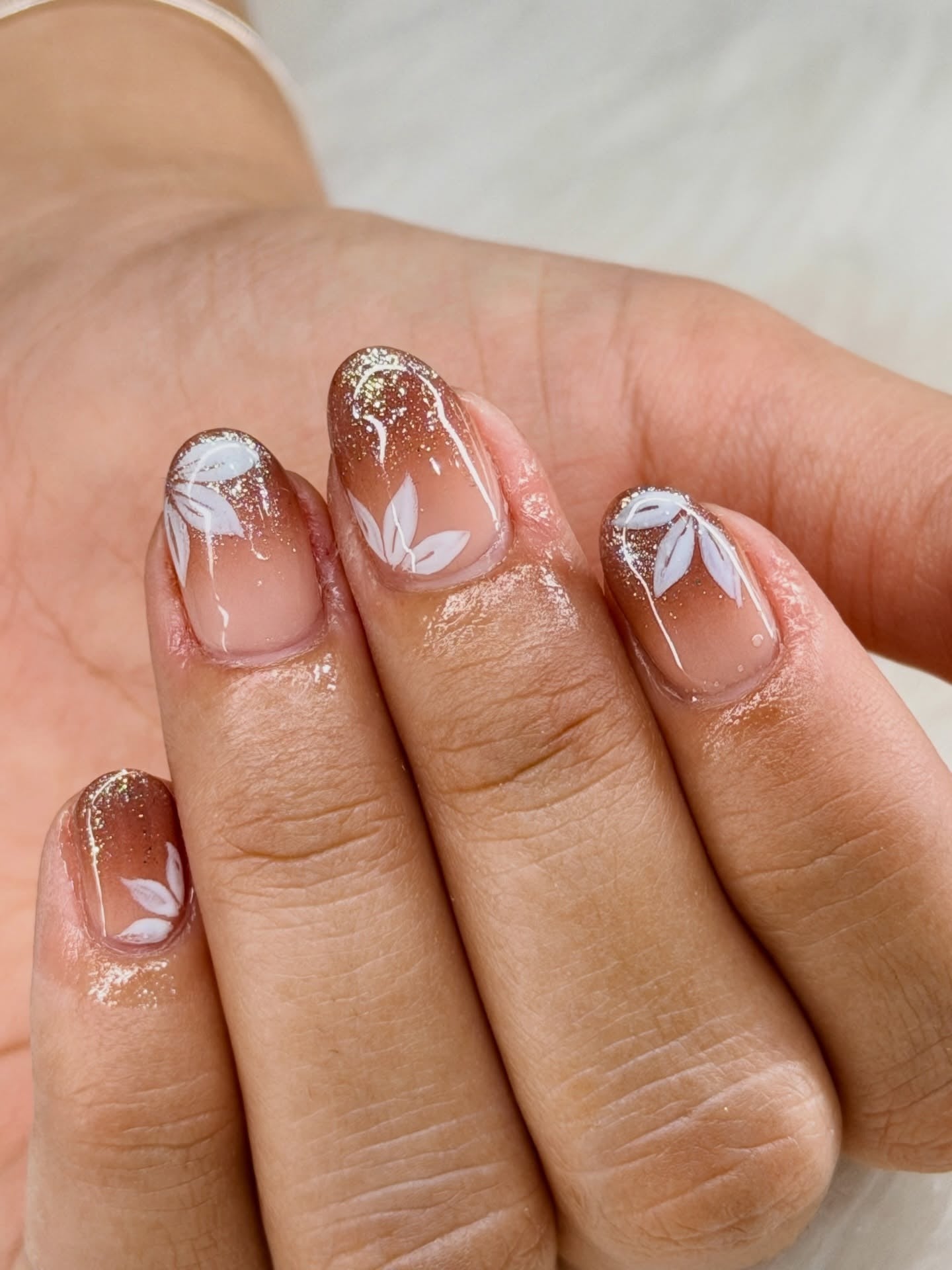 Short nails with floral art and glitter, subtle elegance.