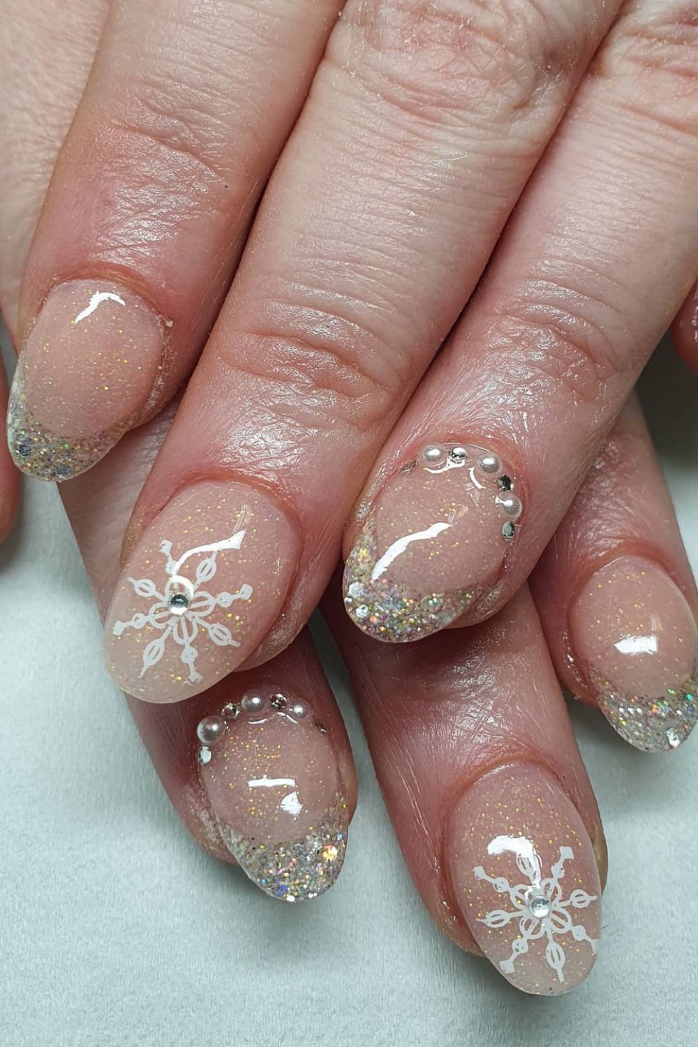 Short nails with snowflake design and glitter, festive wedding theme.