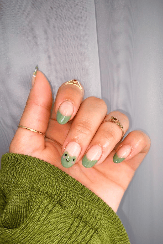 Green French tips with smiley face nail art, playful and quirky.