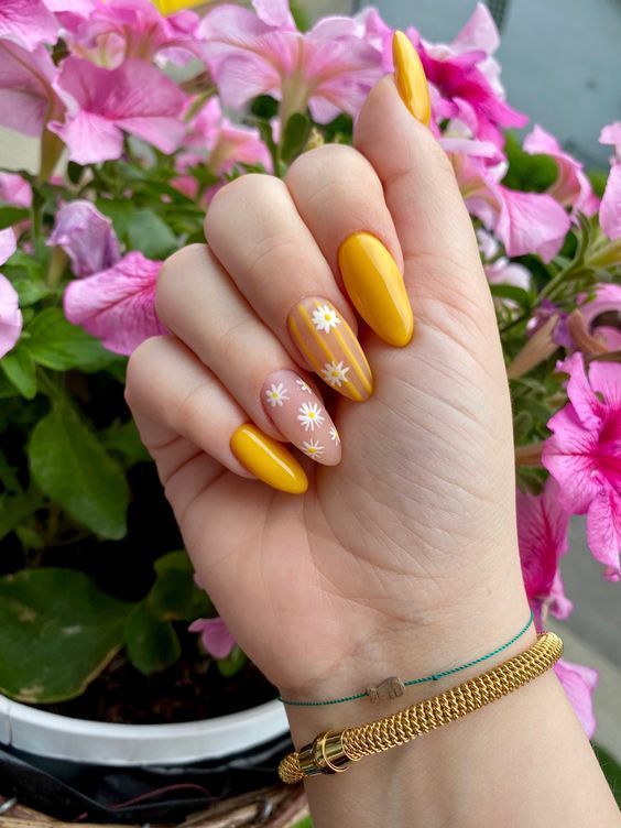 Bold yellow nails with floral accent, vibrant spring style.