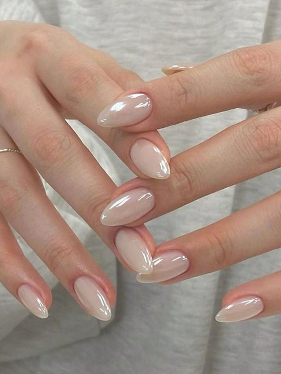 Glazed nude nails, shiny almond manicure.
