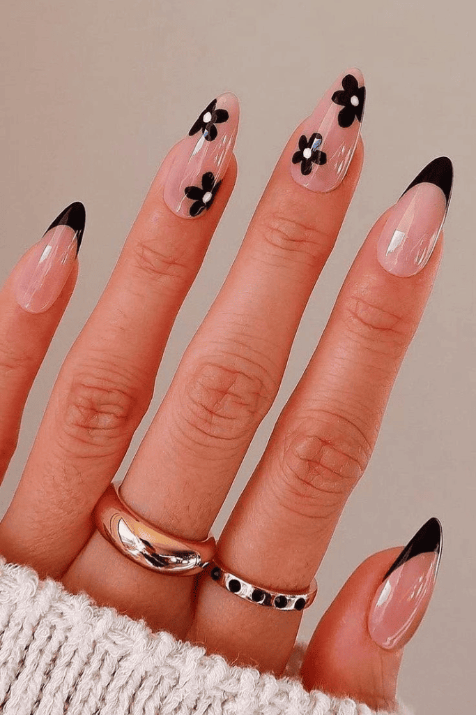 Black floral nail art, bold almond nails.